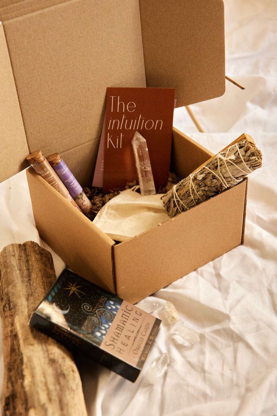 Handmade intuition kit with sage bundle, crystal, bath salts, oracle cards on white fabric