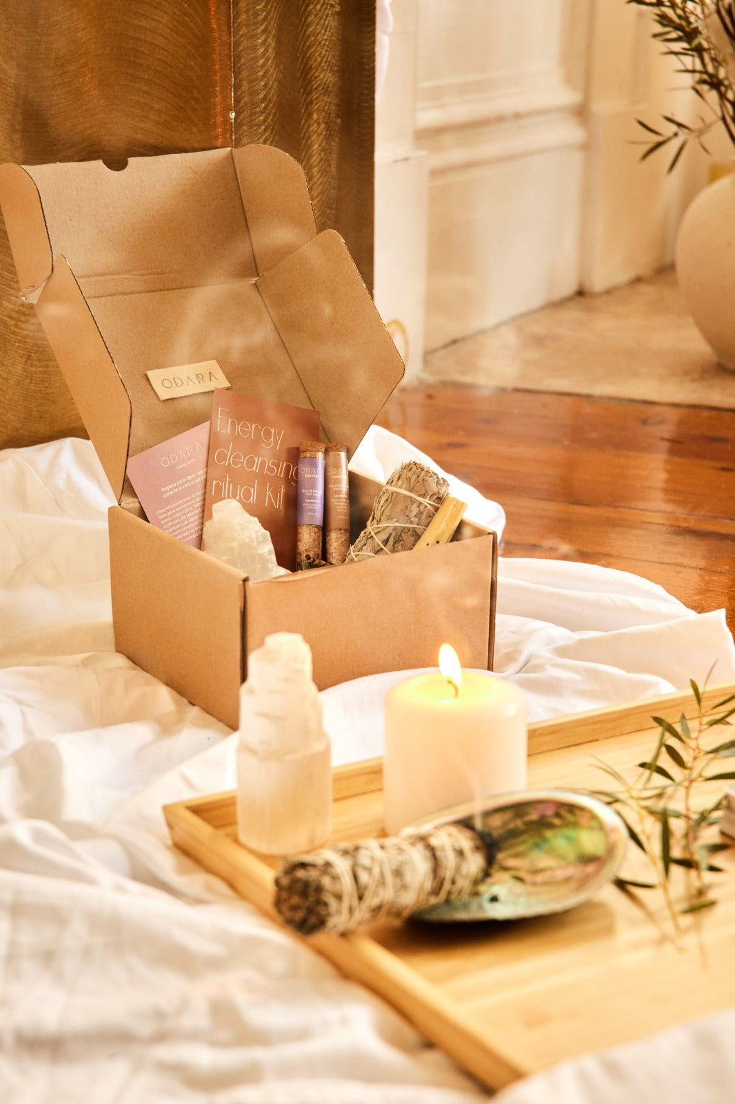 Handmade energy cleansing ritual kit with crystals, sage, candle, and essential oils on wooden tray