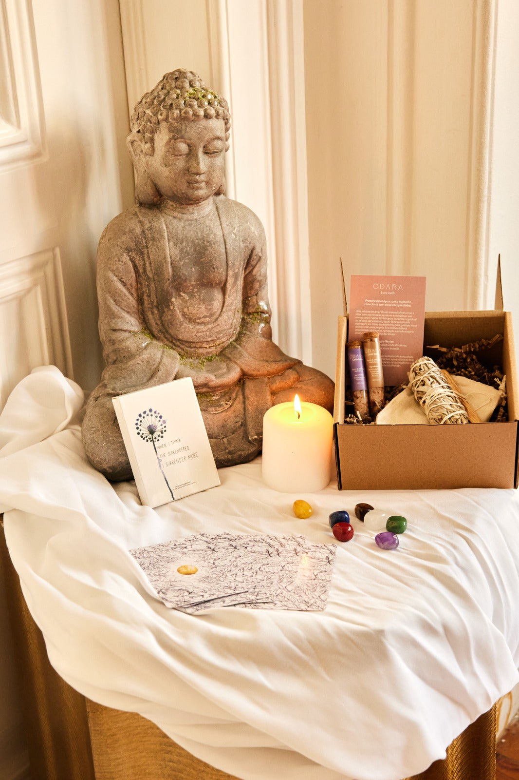 Serene Buddha statue beside meditation kit with candle, crystals, sage stick, and affirmation cards