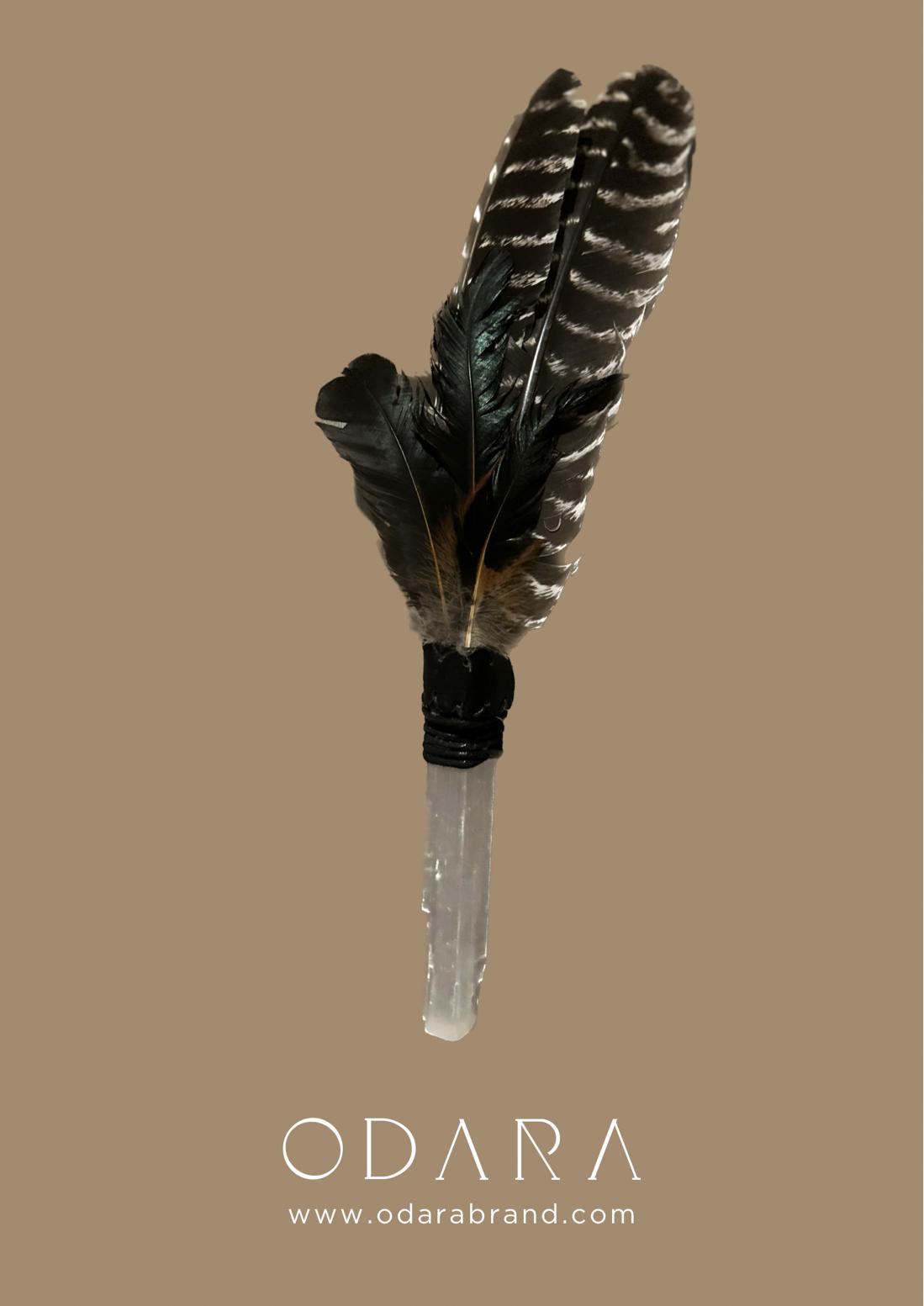 Handmade feather smudge wand with selenite handle against beige background